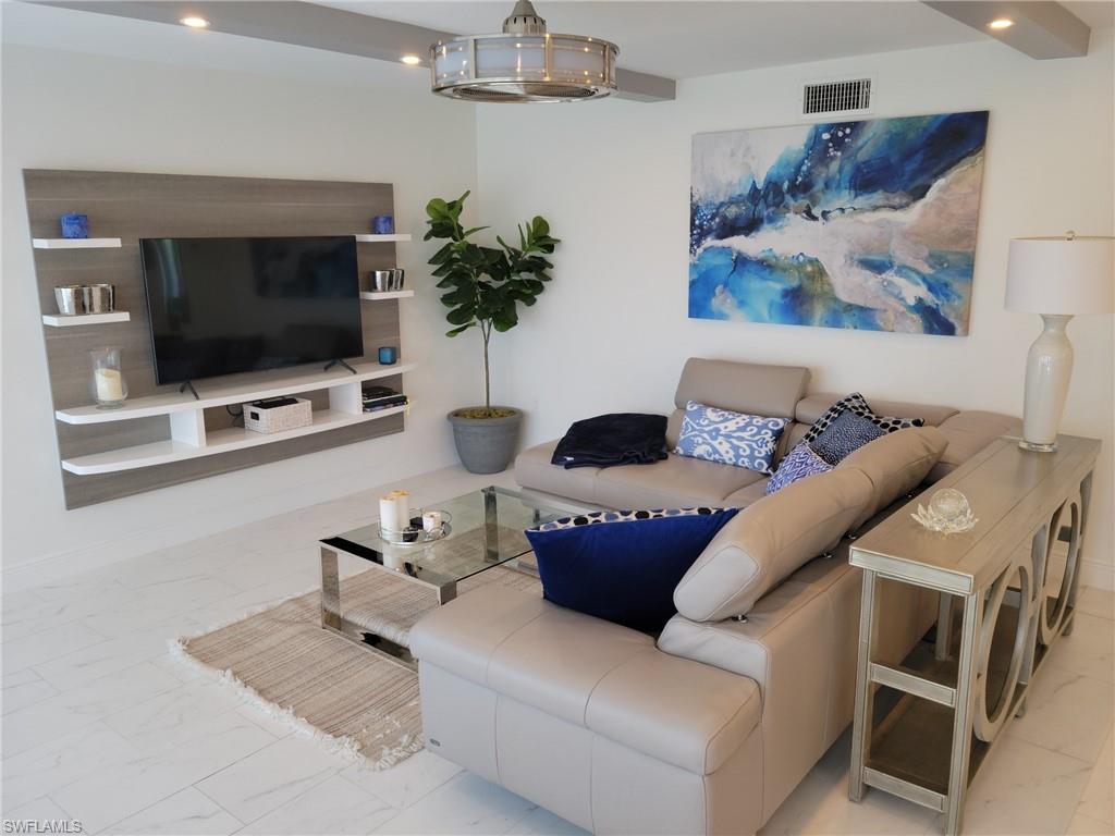 Great room with tile floors, lighted ceiling fan, flat screen TV, leather sofa, recessed lighting.