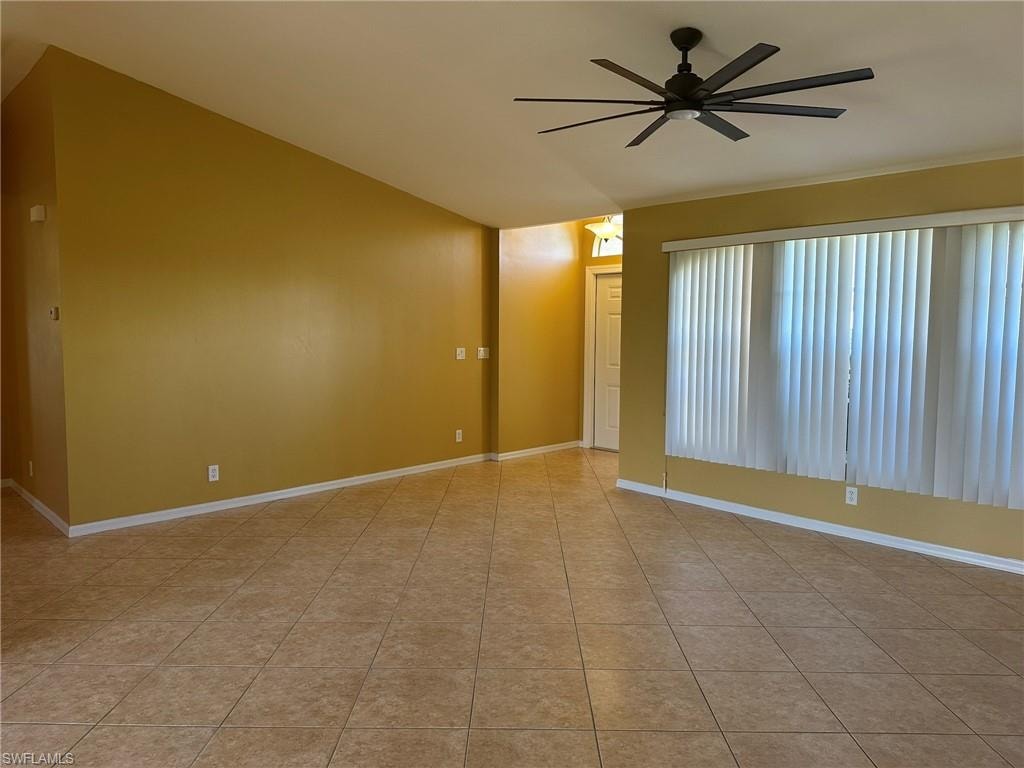 Unfurnished room featuring ceiling fan, vaulted ceiling, and light tile patterned floors