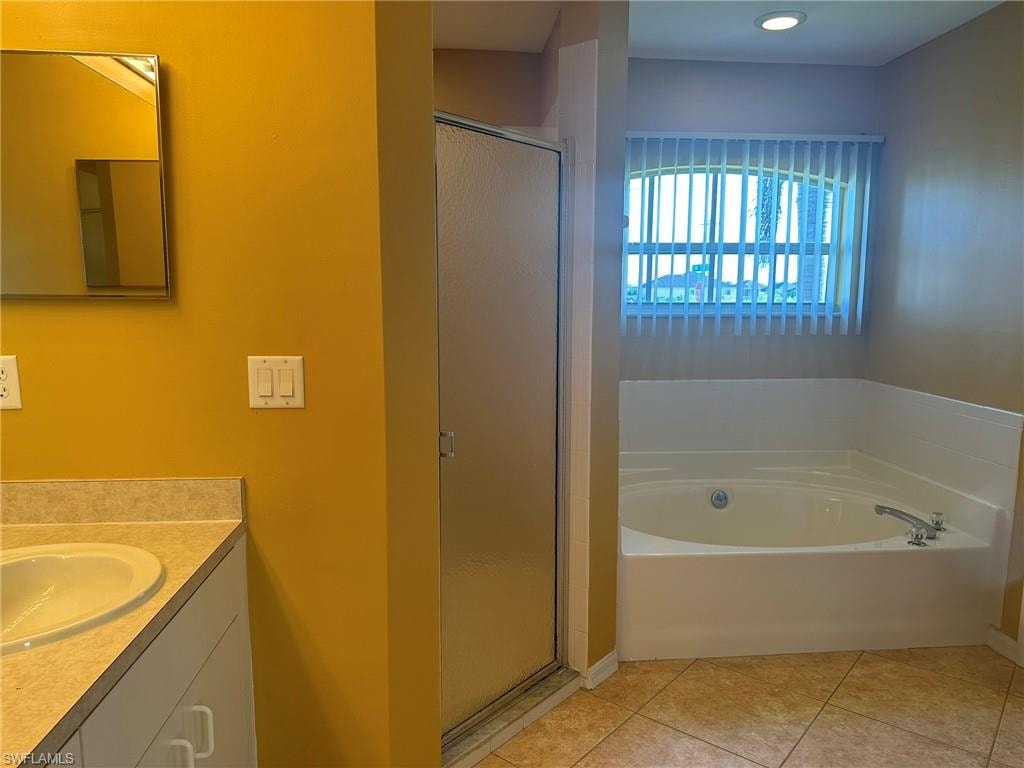 Full bathroom featuring vanity, a garden tub, a stall shower, and light tile patterned floors