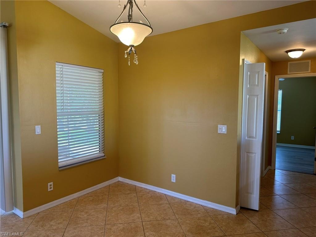 Unfurnished dining area with light tile patterned floors and baseboards
