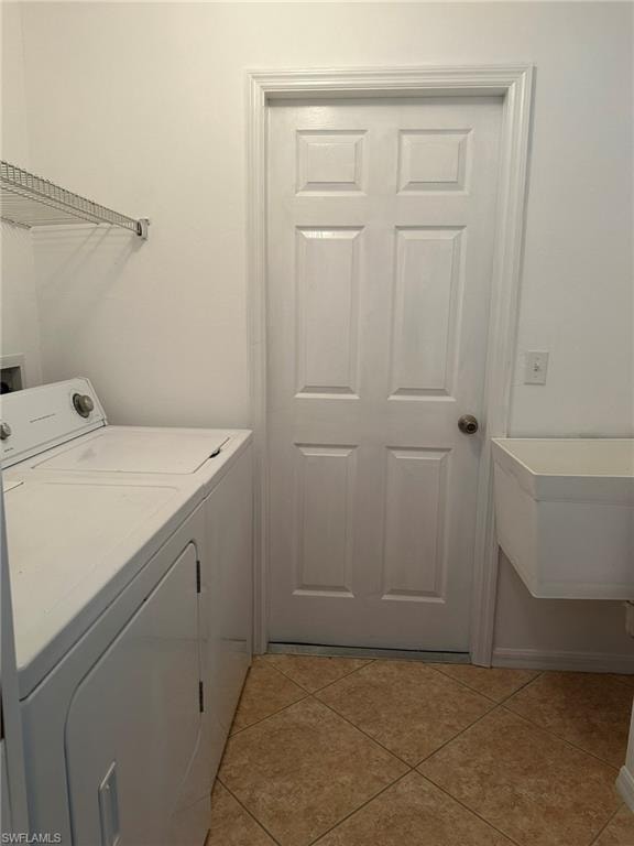 Laundry room featuring light tile patterned floors and washing machine and clothes dryer