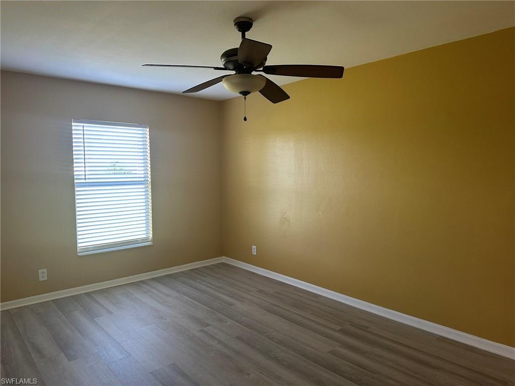Unfurnished room featuring a ceiling fan and dark wood-style flooring