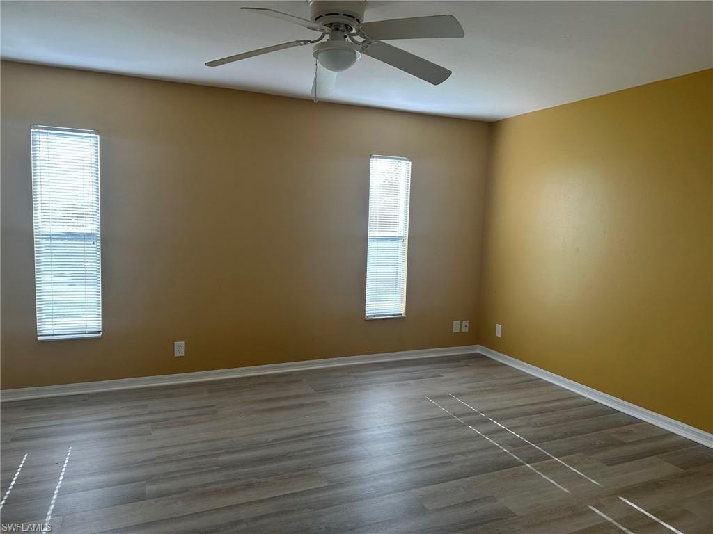 Unfurnished room with dark wood finished floors and a ceiling fan