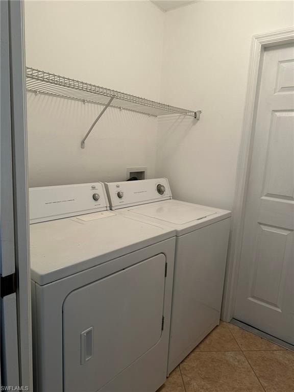 Laundry room with independent washer and dryer and light tile patterned floors