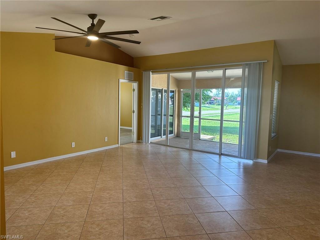 Empty room with vaulted ceiling, ceiling fan, and light tile patterned flooring