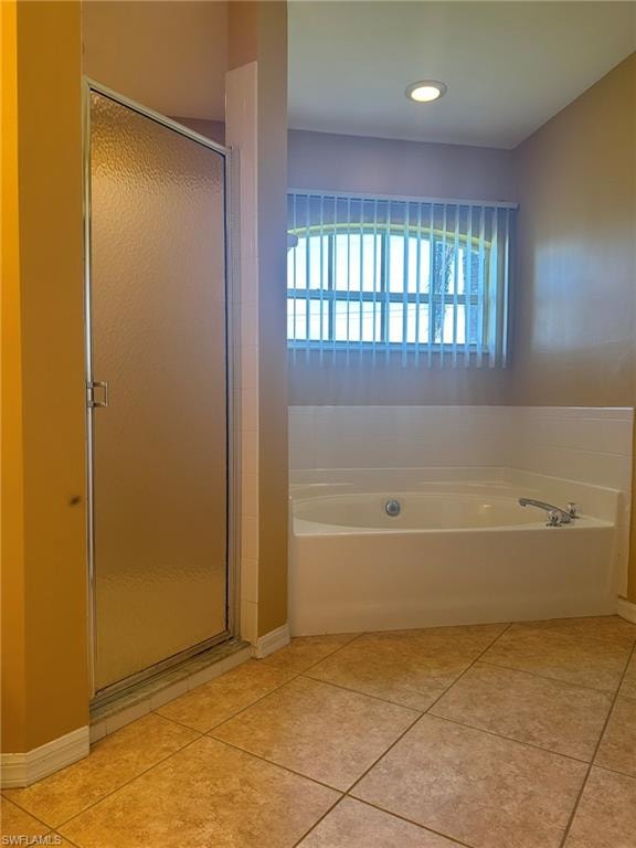 Bathroom featuring a garden tub, a stall shower, and light tile patterned floors