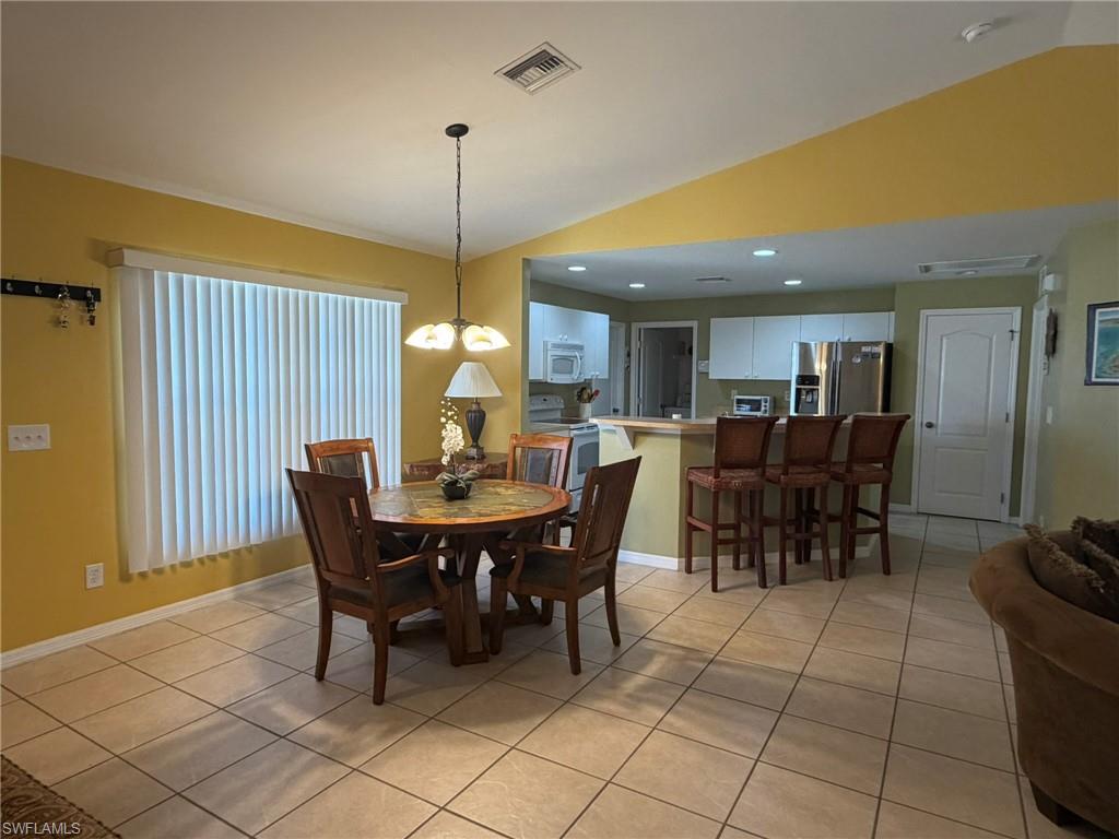 Dining room featuring vaulted ceiling, light tile patterned flooring, and a chandelier