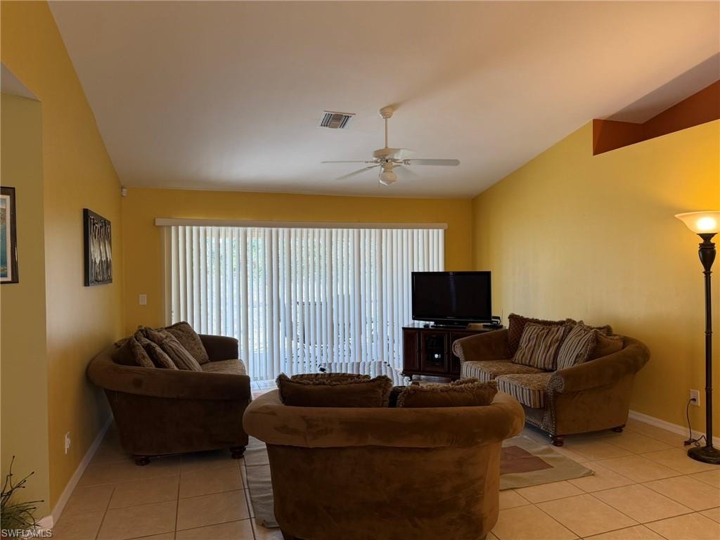 Living area featuring ceiling fan, lofted ceiling, plenty of natural light, and light tile patterned flooring