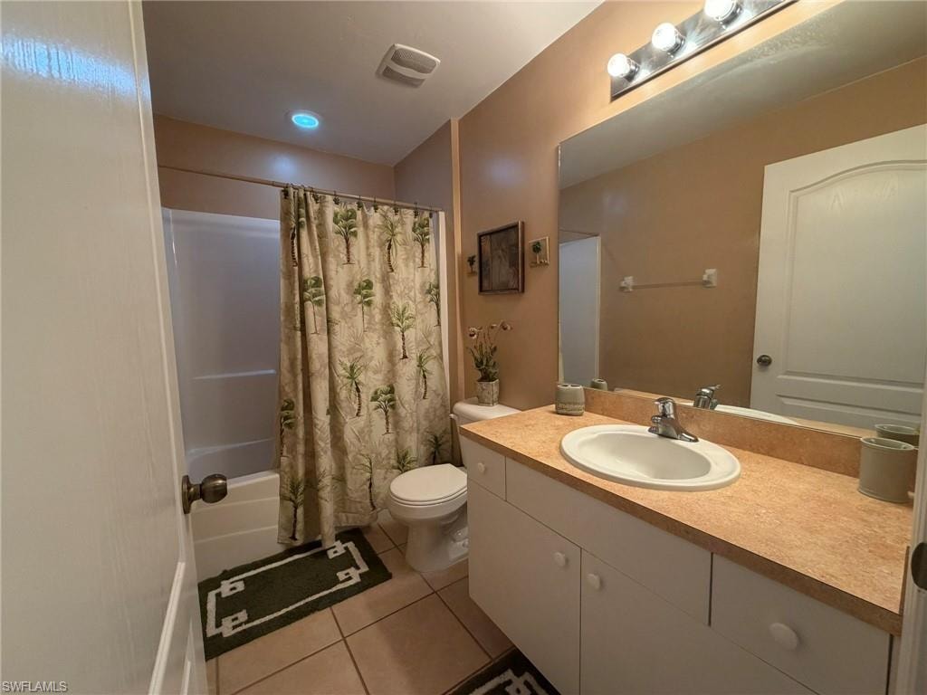 Bathroom featuring vanity, shower / bath combo with shower curtain, and light tile patterned flooring