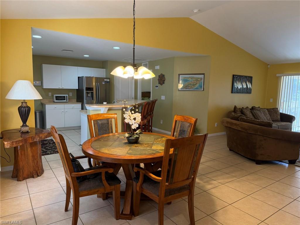 Dining area with light tile patterned floors, lofted ceiling, and hanging lights