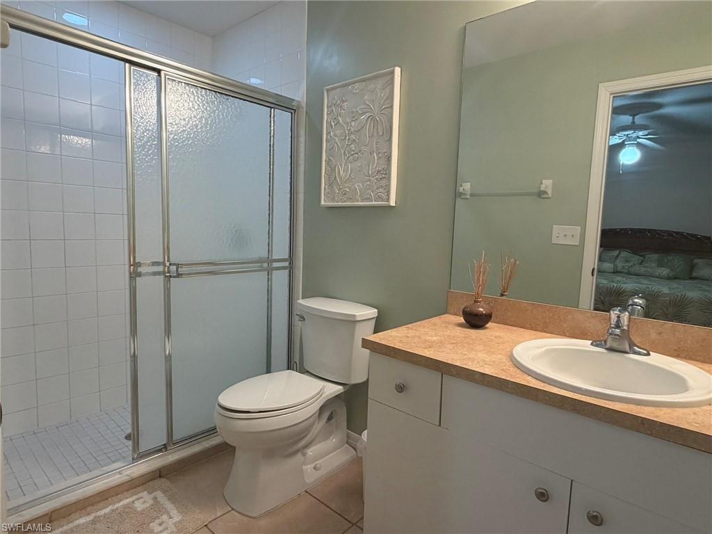 Full bathroom with ensuite bath, vanity, a stall shower, light tile patterned floors, and ceiling fan