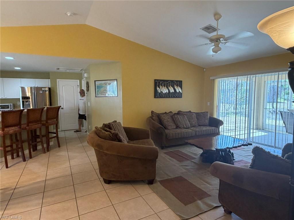 Living area with light tile patterned flooring, ceiling fan, and lofted ceiling