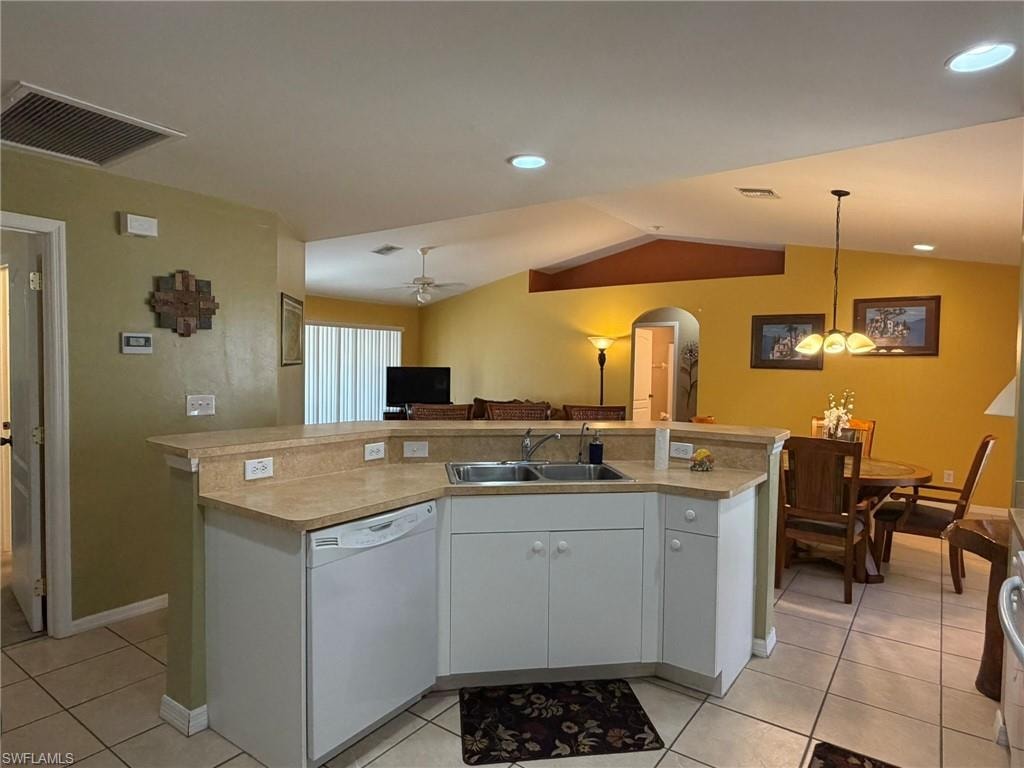 Kitchen featuring a center island with sink, dishwasher, light countertops, arched walkways, and open floor plan