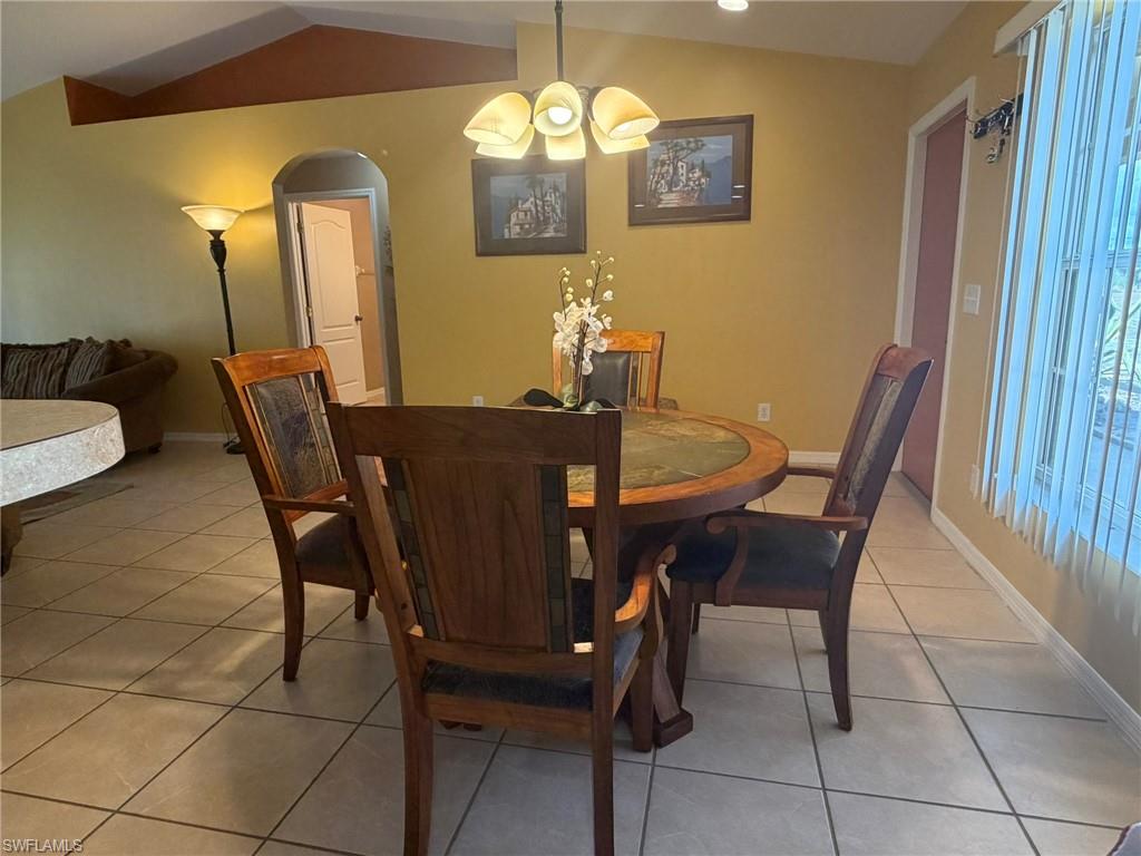Dining room featuring arched walkways and light tile patterned flooring