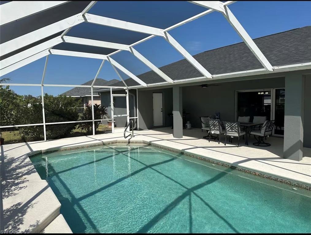 Swimming pool with glass enclosure, a sunroom, a patio area, and outdoor dining area