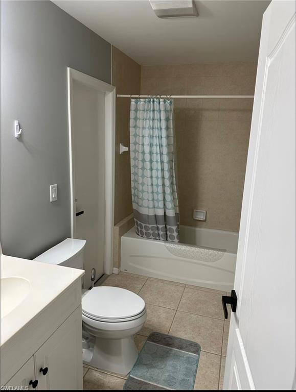 Full bathroom featuring vanity, shower / tub combo with curtain, and light tile patterned flooring