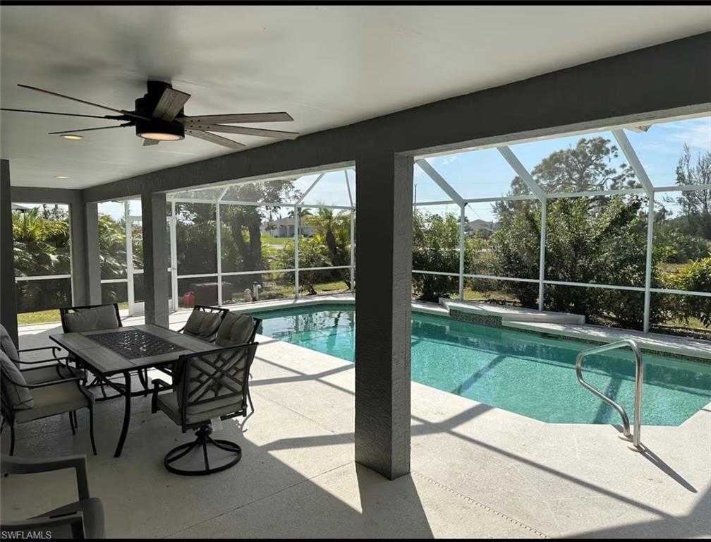 Outdoor pool featuring a patio area, outdoor dining space, glass enclosure, and a sunroom