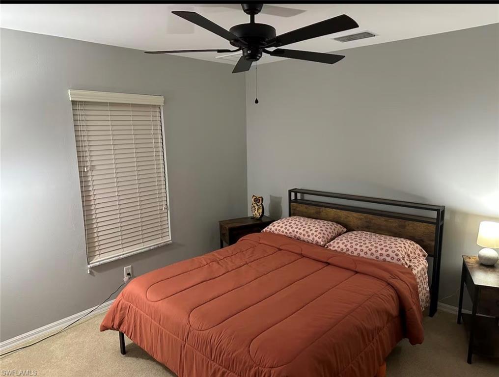 Carpeted bedroom with ceiling fan and baseboards