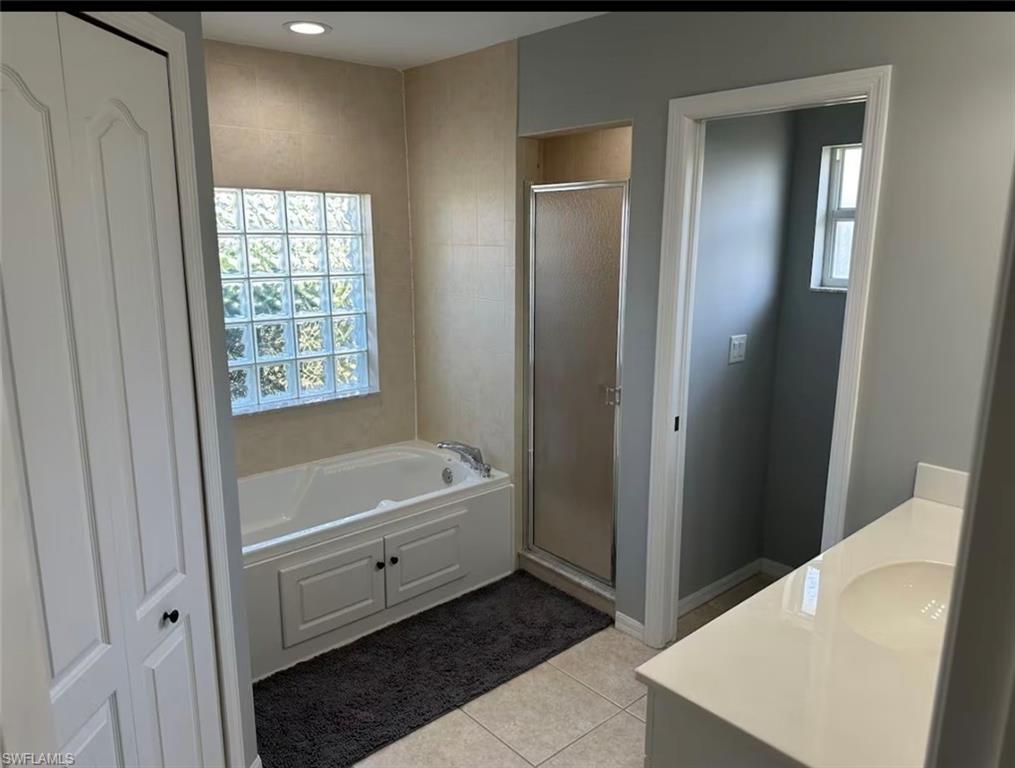 Full bathroom with vanity, a shower stall, healthy amount of natural light, and light tile patterned floors