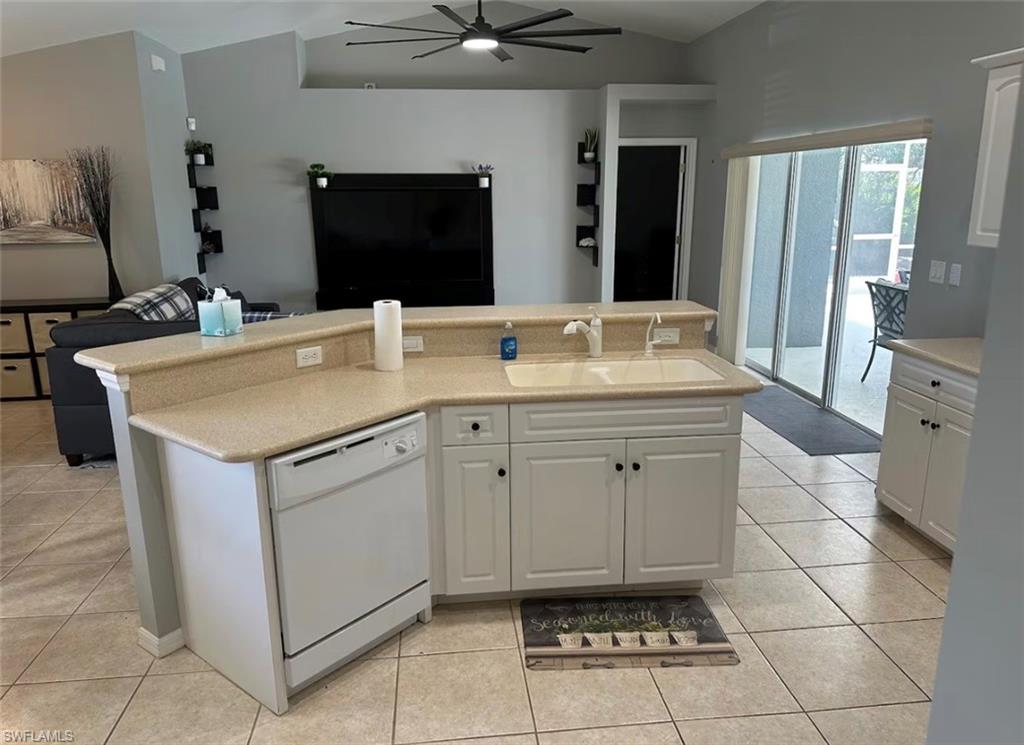 Kitchen with open floor plan, ceiling fan, dishwasher, and white cabinetry