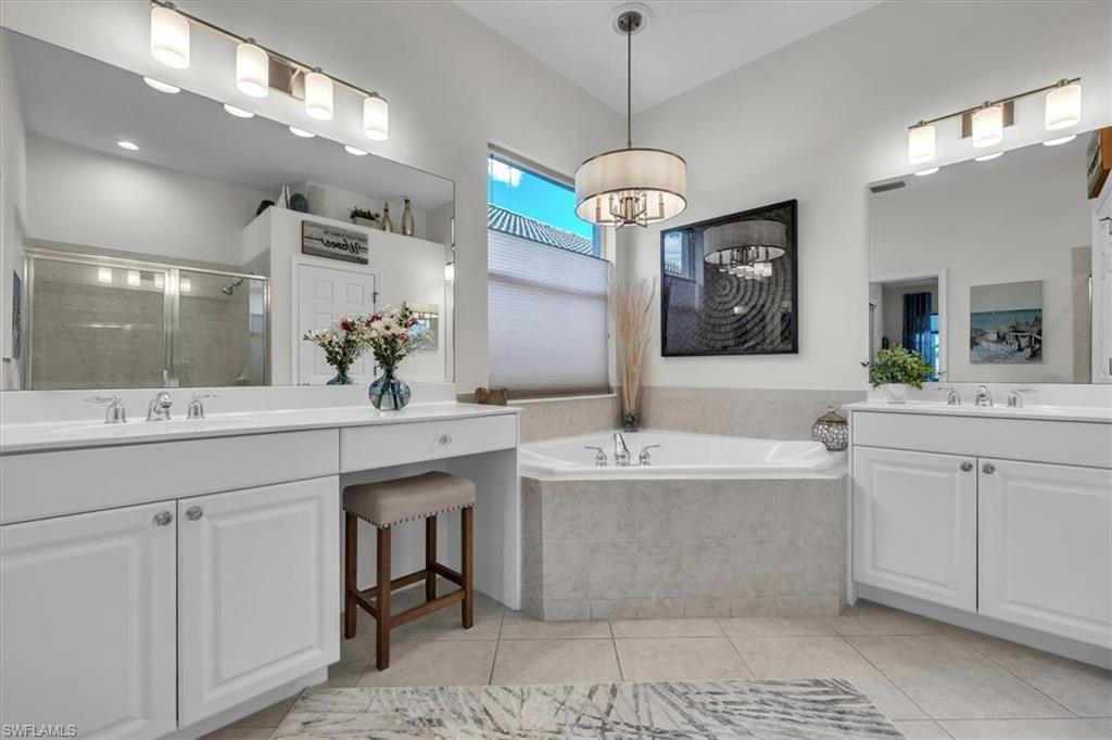 Full bathroom featuring two vanities, a stall shower, a bath, and light tile patterned floors