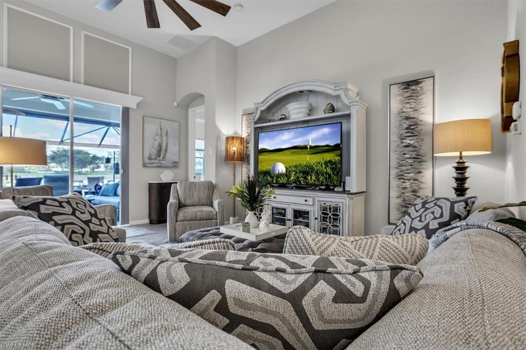Living area featuring a ceiling fan, a high ceiling, a sunroom, and arched walkways
