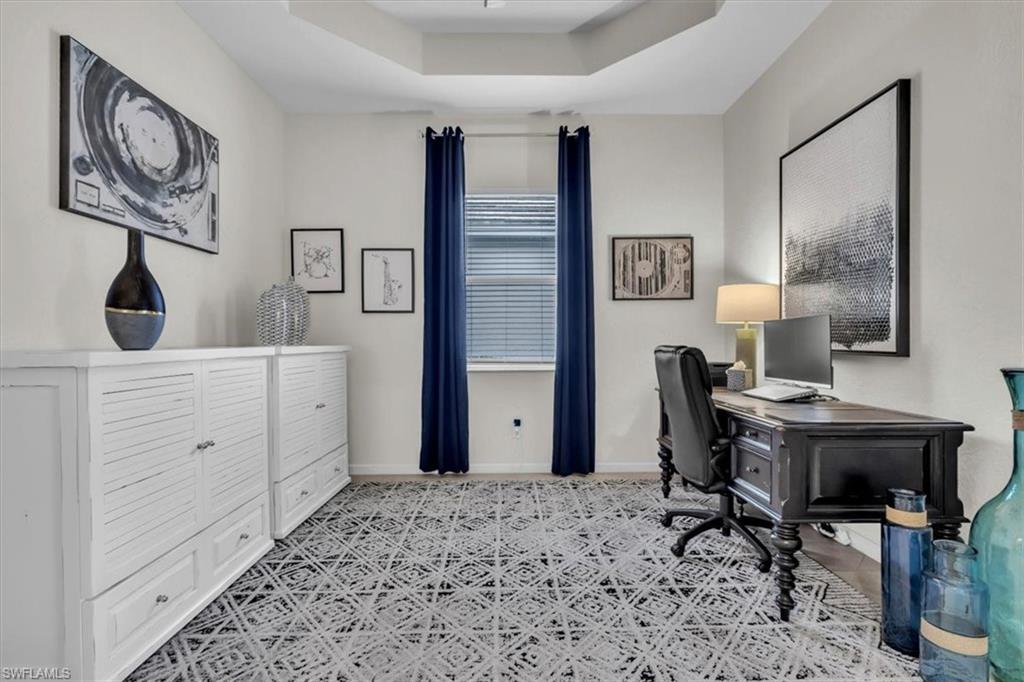 Home office with a raised ceiling and baseboards