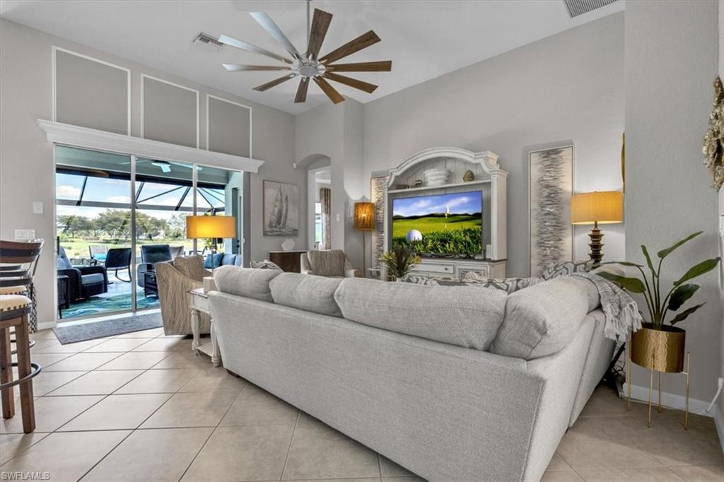 Living room with a sunroom, ceiling fan, a high ceiling, and light tile patterned flooring