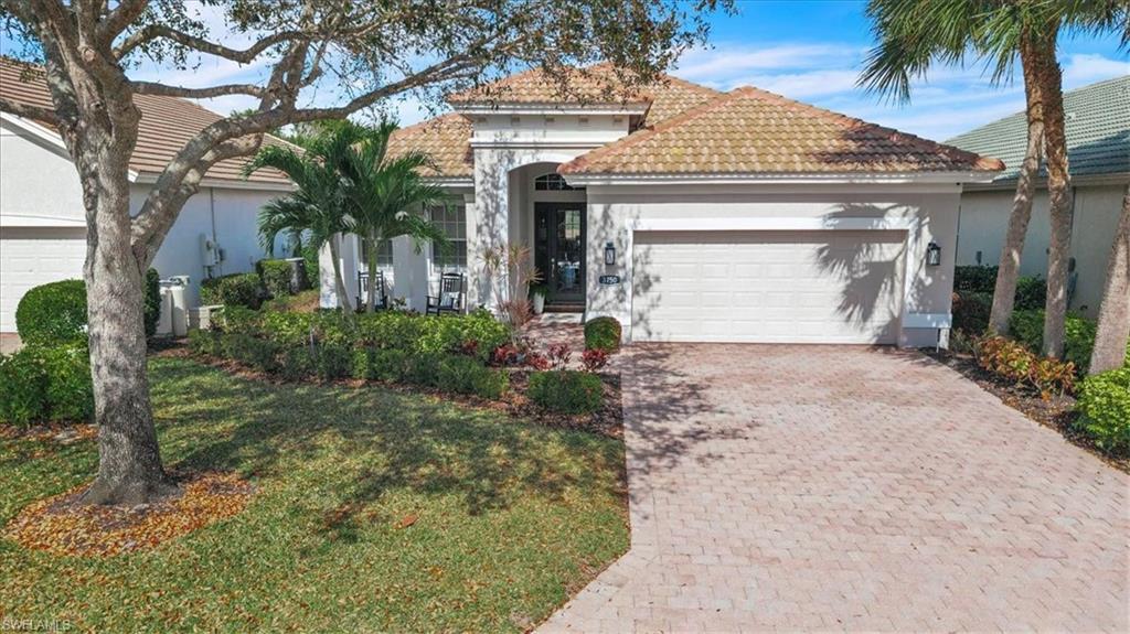 Mediterranean / spanish-style house with a garage, decorative driveway, stucco siding, and a tile roof