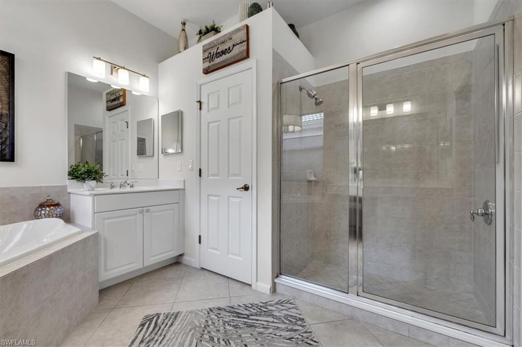 Bathroom with a shower stall, vanity, a bath, and light tile patterned floors
