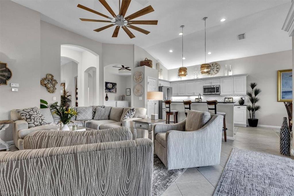 Living area featuring ceiling fan, light tile patterned flooring, lofted ceiling, arched walkways, and recessed lighting
