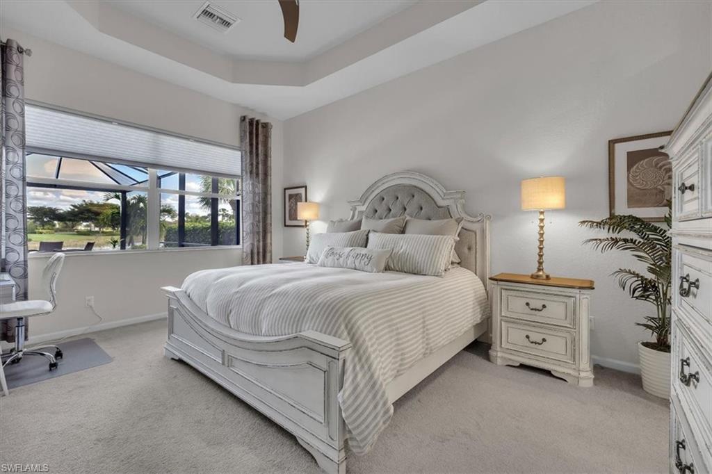 Bedroom featuring a tray ceiling, light carpet, and a ceiling fan