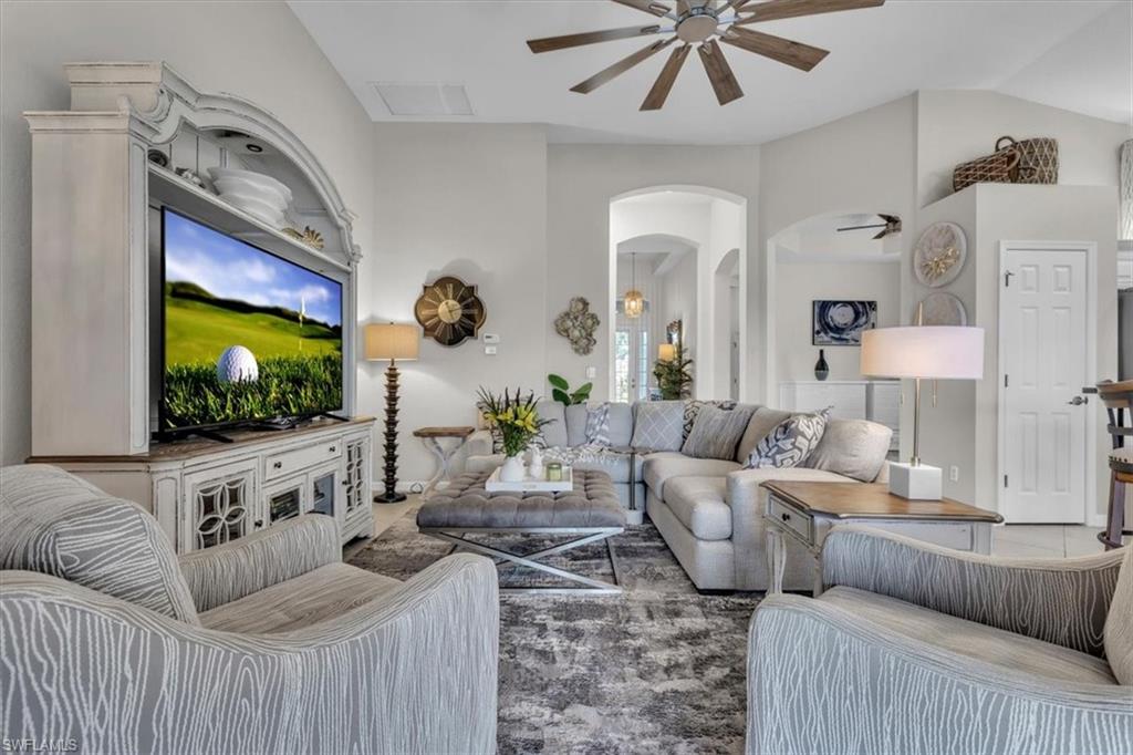 Living room featuring ceiling fan, arched walkways, and lofted ceiling