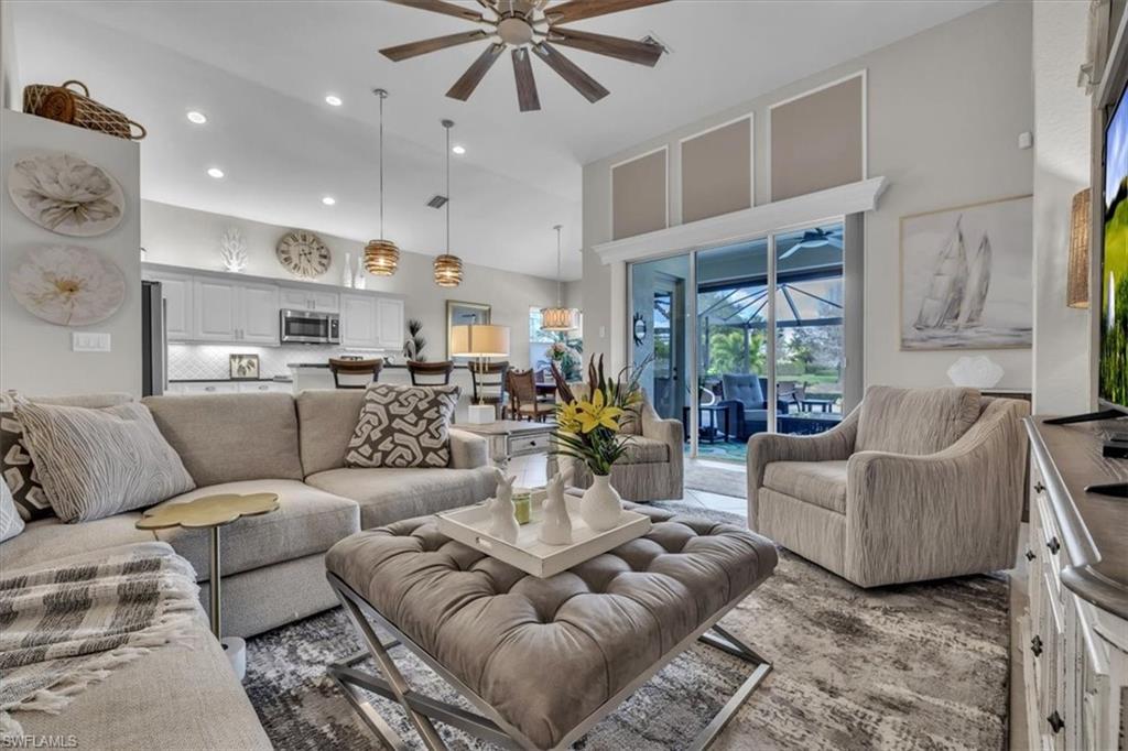 Living room with a ceiling fan, a sunroom, a high ceiling, and recessed lighting