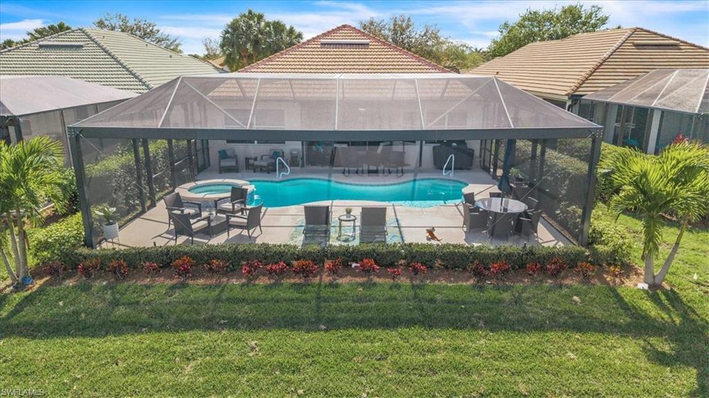 Integrated pool / hot tub featuring a sunroom, a lanai, a patio area, and a lawn