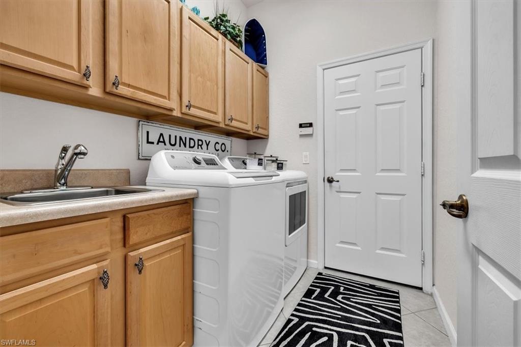 Laundry area with cabinet space, washing machine and dryer, and light tile patterned floors