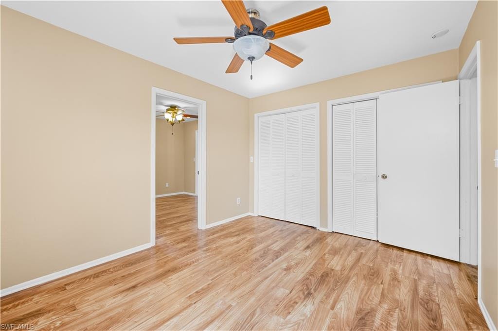 Unfurnished bedroom featuring two closets, light wood-type flooring, and a ceiling fan