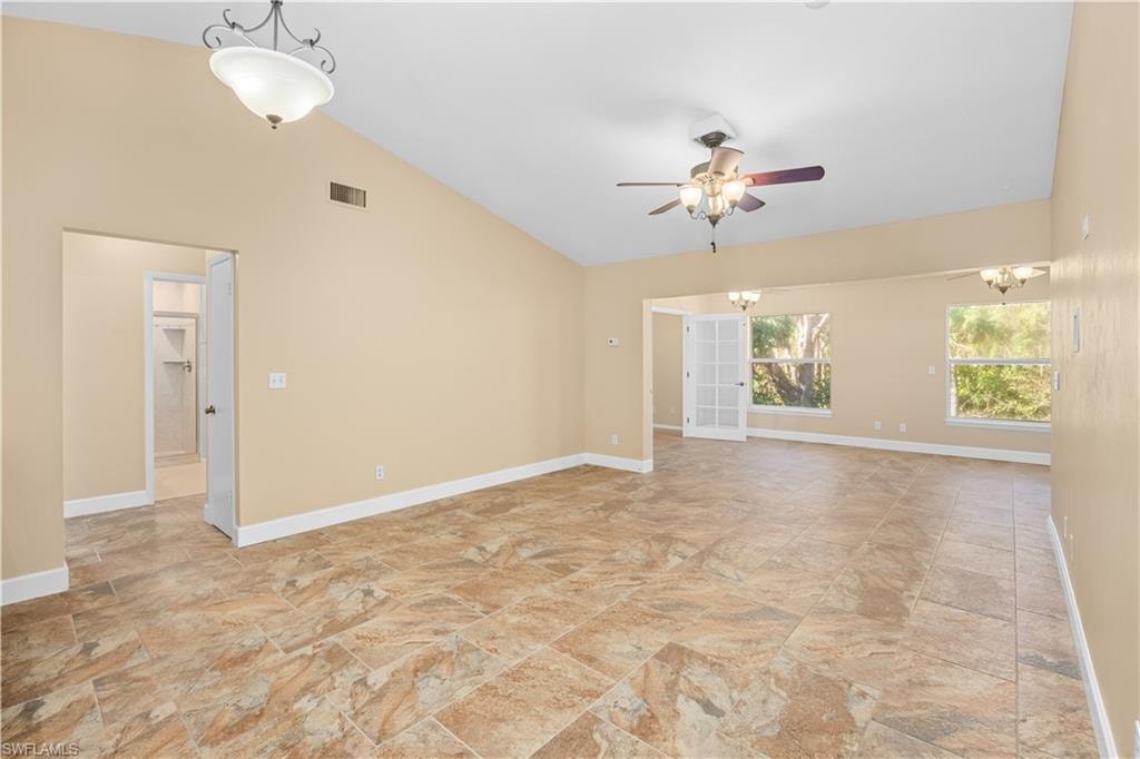 Unfurnished room featuring lofted ceiling, ceiling fan, and suspended lighting