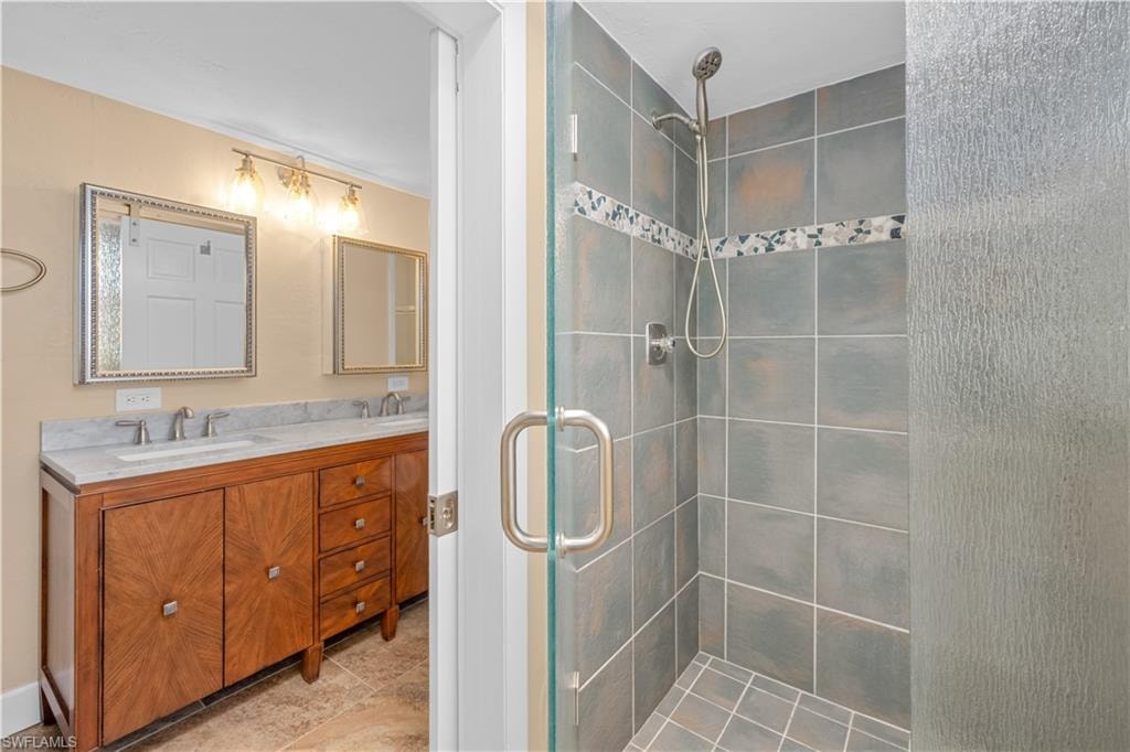 Full bath with double vanity and a shower stall