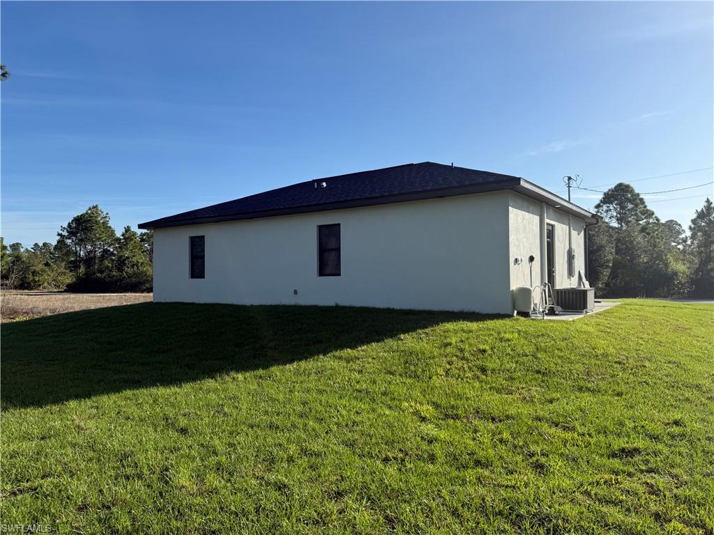 View of side of property with a yard and stucco siding