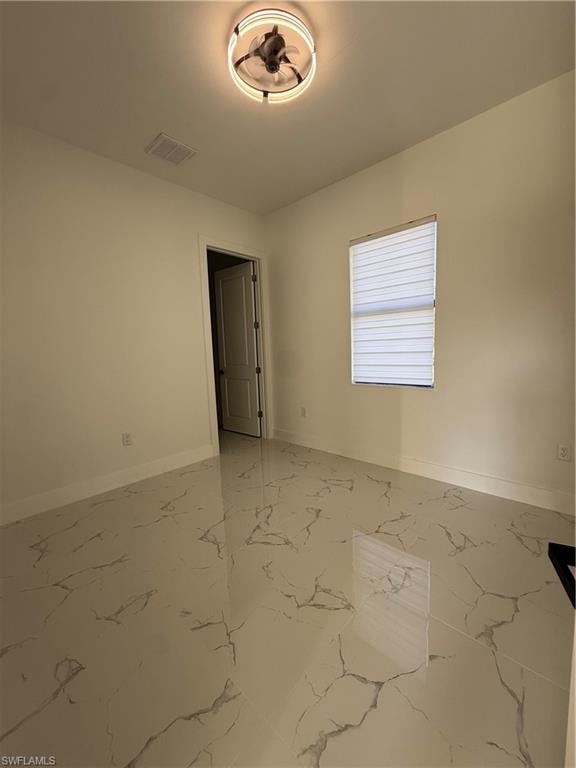 Unfurnished room featuring baseboards and light marble finish floors