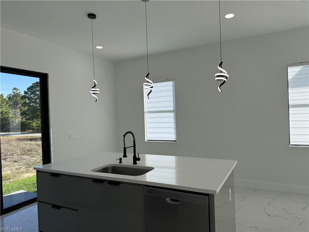 Kitchen featuring light marble finish flooring, dishwasher, hanging light fixtures, and a kitchen island with sink