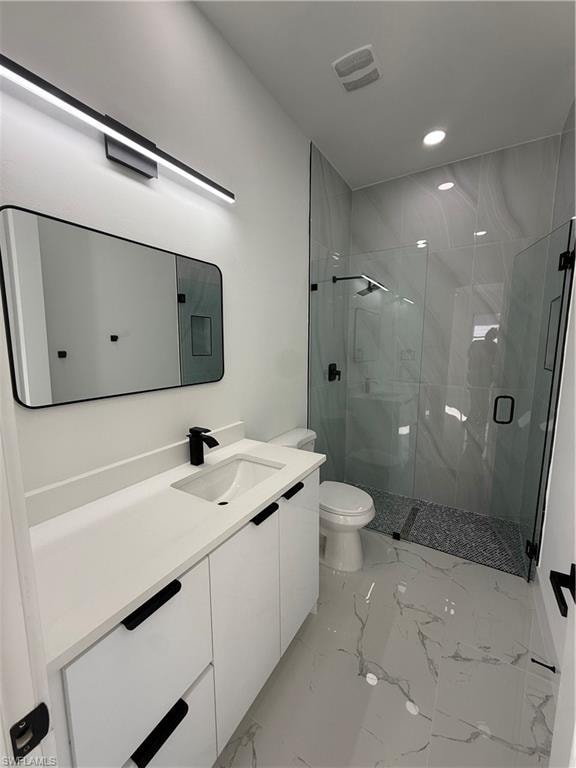 Bathroom featuring vanity, a marble finish shower, recessed lighting, and light marble finish flooring
