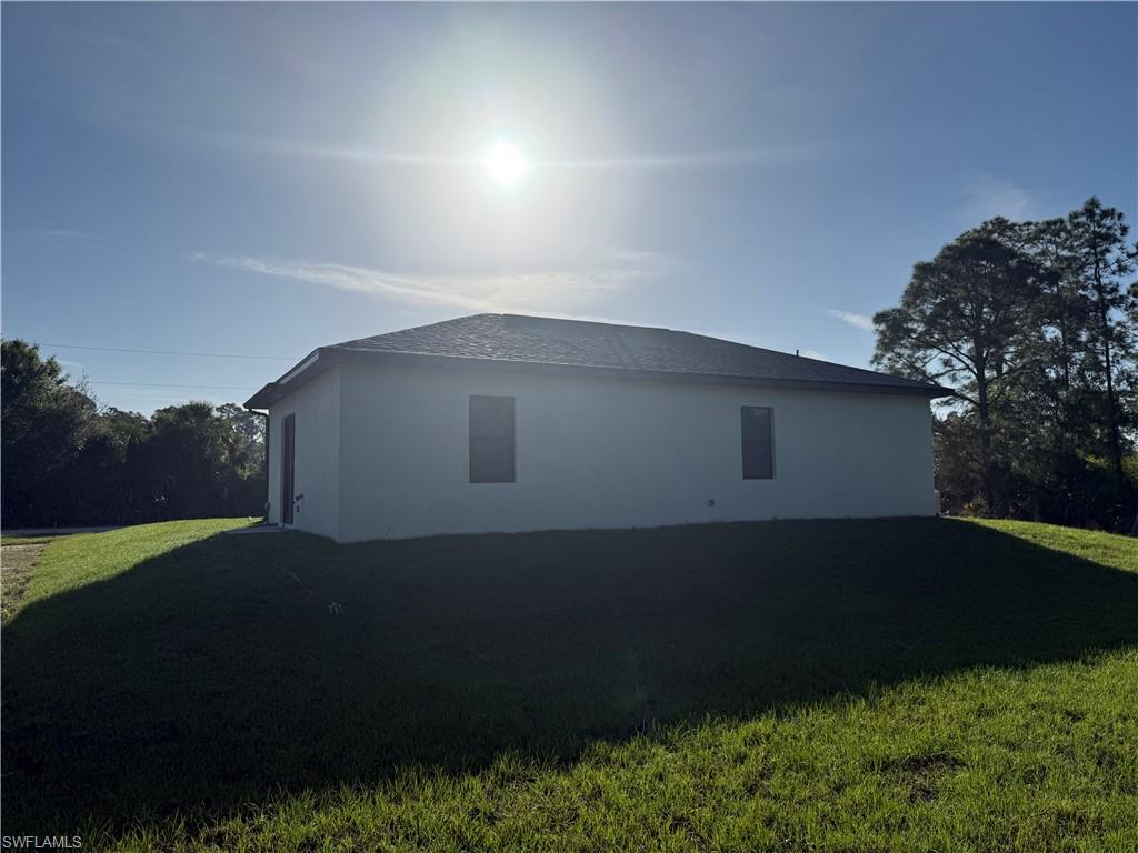 View of side of home with a yard and stucco siding