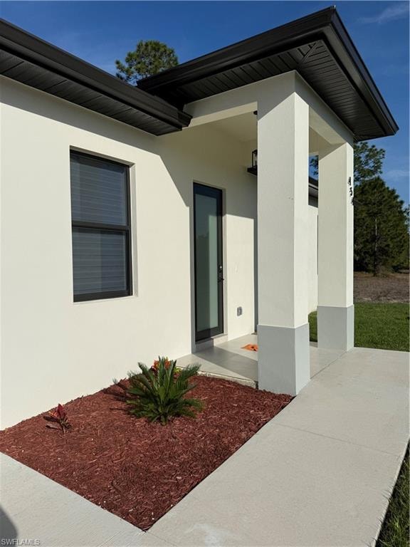 View of exterior entry featuring stucco siding and covered porch