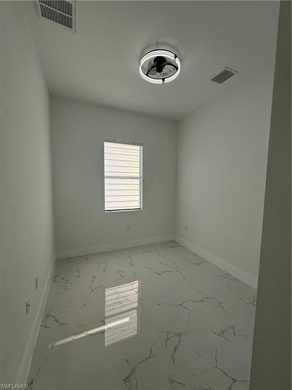 Empty room featuring light marble finish floors and baseboards