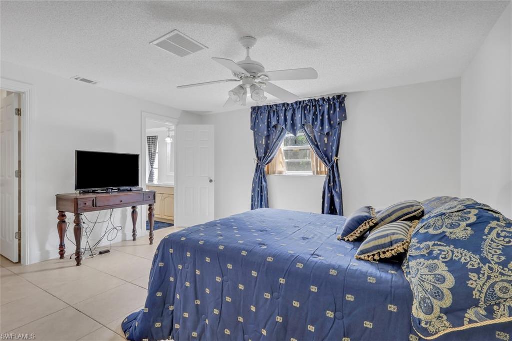 Bedroom with a textured ceiling, ceiling fan, and light tile patterned floors