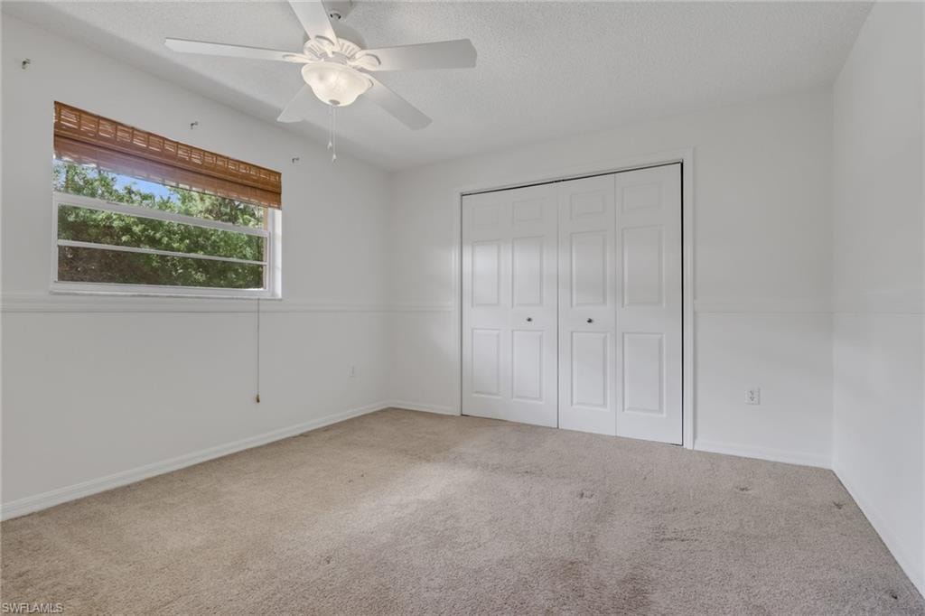 Unfurnished bedroom featuring carpet, a closet, ceiling fan, and a textured ceiling
