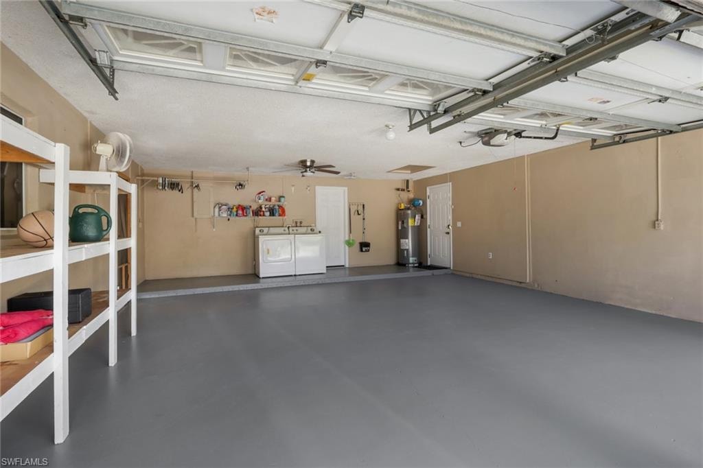 Garage with washer and dryer, water heater, and a ceiling fan