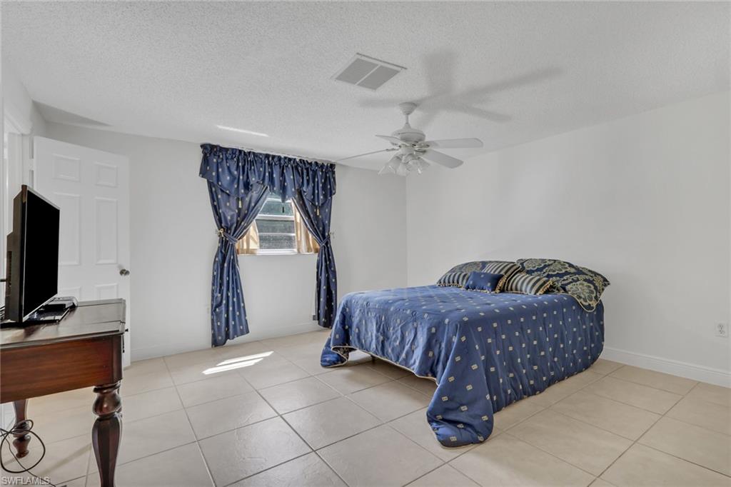 Bedroom with a textured ceiling, ceiling fan, and light tile patterned floors